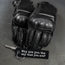 Black motorcycle gloves and keychain with motivational quote on a dark background