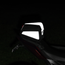 A black motorcycle pillion seat bag with reflective white panels, mounted on the rear seat of a motorcycle at night.