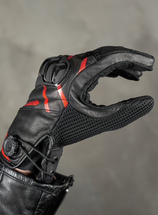 Black motorcycle glove with red accents on a gray background