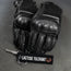 Black motorcycle gloves with a keychain labeled 'Lactose Tolerant' on a gray background